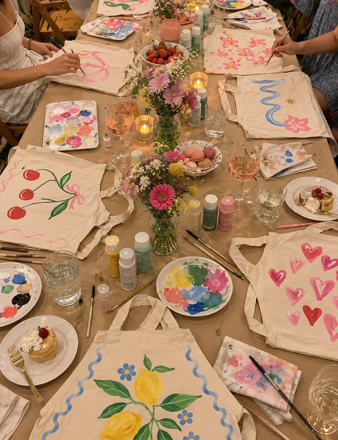 Guests gathered around a long craft table painting aprons