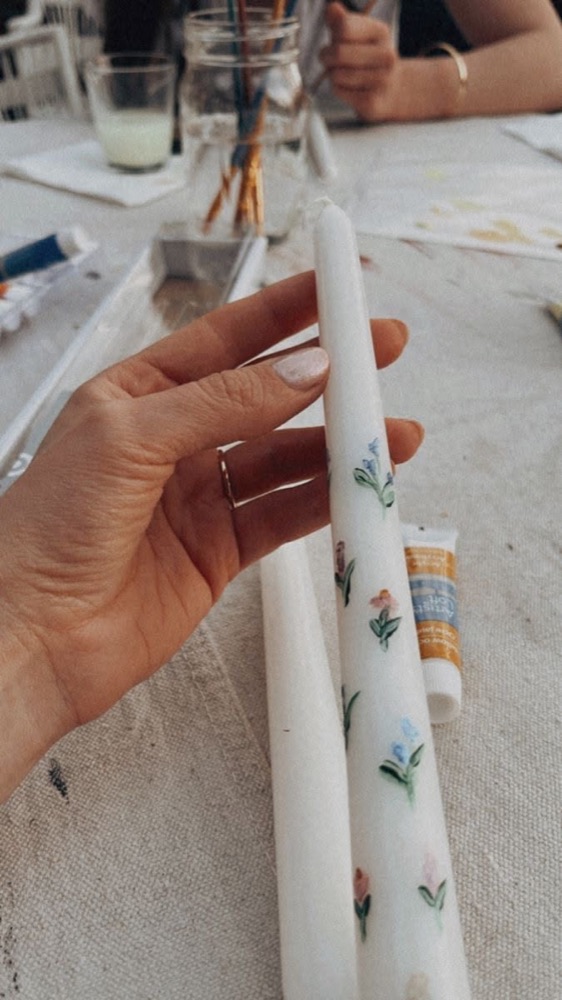 A hand-painted taper candle with small blue flowers