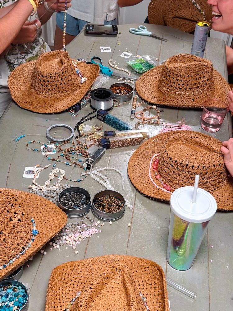 Friends decorating straw hats around a table